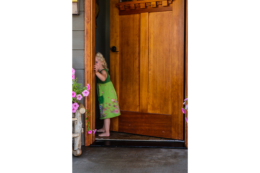 The young girl peeks shyly backward as she goes in the door.